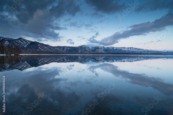 Fototapeta 黄昏の湖の水面に映る淡い青の空。