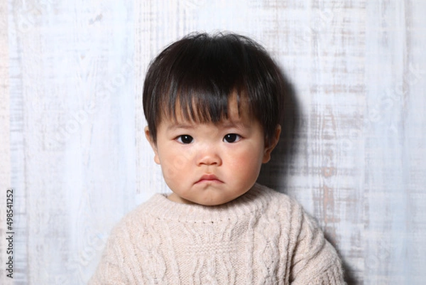 Fototapeta セーターを着た真顔の女の子（オカッパ）。