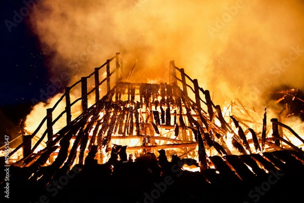 Fototapeta Burning collapsing wooden bridge in a raging flame close-up. Bridge on fire at dark night. Fiery bridge through the flames of fire. Transition in Bright Hellfire. Bridge during intense combustion.