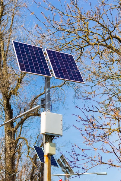 Fototapeta Close-up of a modern photovoltaic solar array against the background of trees and blue sky