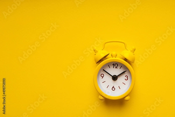 Fototapeta Yellow alarm clock on a yellow background.