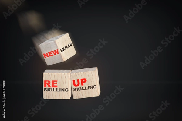 Fototapeta Reskilling, upskilling and new skills written on wooden cube isolated on black background. Future of work concept