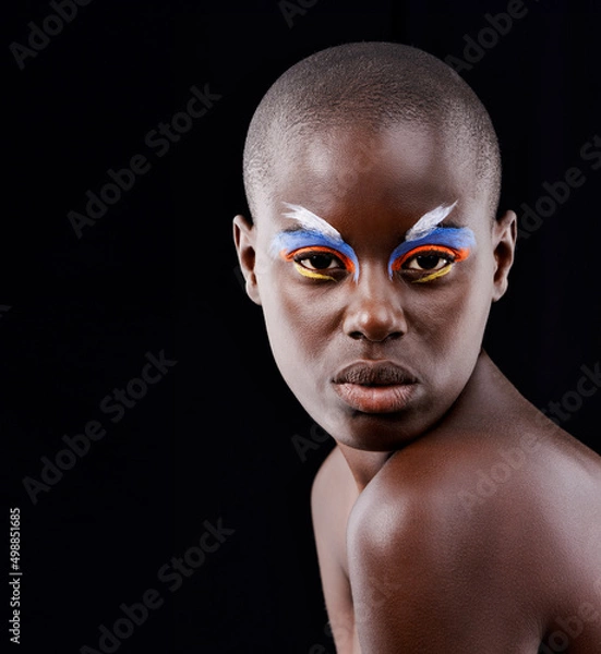 Fototapeta A wild and colorful spirit. Studio portrait of a beautiful model posing with colorful eye makeup on a black background.