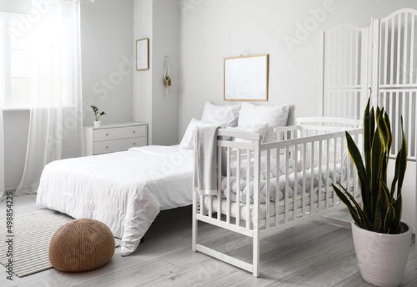 Fototapeta Modern interior of cozy room with big bed and comfortable baby crib