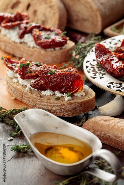 Fototapeta Bruschetta with ricotta, sun-dried tomatoes, and thyme.