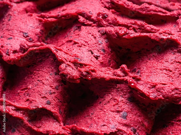 Fototapeta Frozen Black Currant flavour gelato - full frame detail of sorbet. Close up of a red surface texture of Ice cream filled with pieces of mixed fruit.