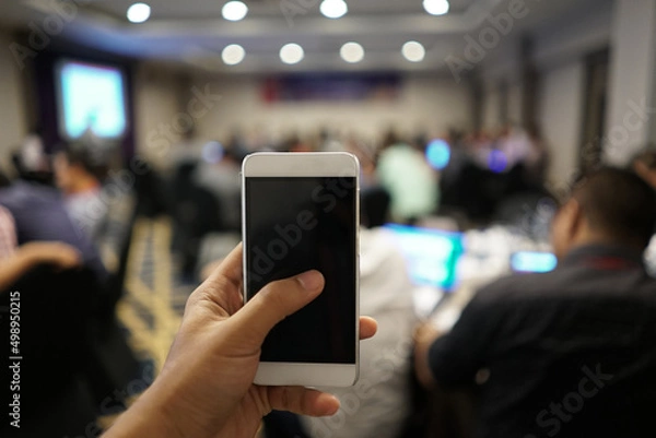 Fototapeta Mobile hold in hand with blur meeting room