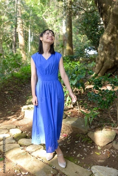 Obraz 初夏の新緑を背景に微笑む青いドレスを着た微笑む若い女性	