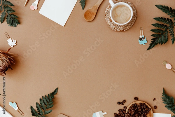 Obraz Top view brown neutral workspace office desk with coffee and office supplies. Flat lay work table with craft notebook, green olive leaf and supplies. Home blogger