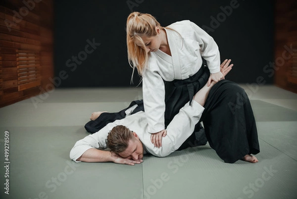Fototapeta A man and a woman practice aikido indoor