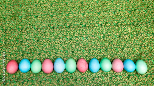 Fototapeta Easter eggs of different colors on a green background. Multi-colored chicken eggs for the Easter holiday.