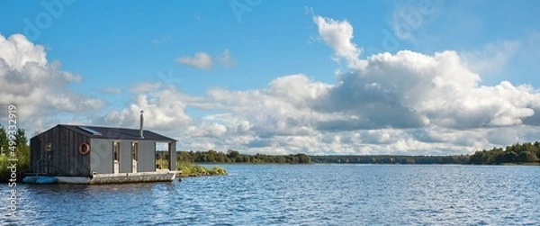 Fototapeta A modern houseboat in an open river landscape. The concept of summer holidays near the river. Wide banner, copy space.