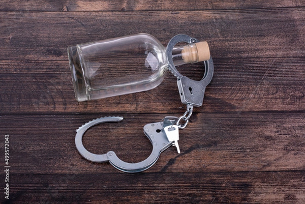 Fototapeta The concept of liberation from alcohol addiction, a bottle of alcohol and unfastened handcuffs