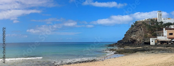 Fototapeta Cliffs at the end of beautiful morro jable beach on fuerteventura island under a blue cloudy sky