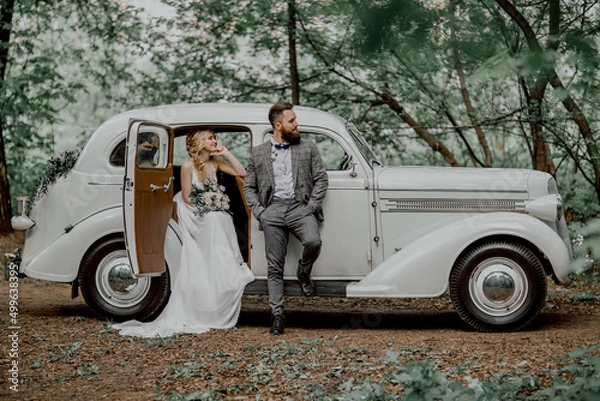 Obraz The bearded groom and beautiful bride. Retro car.
