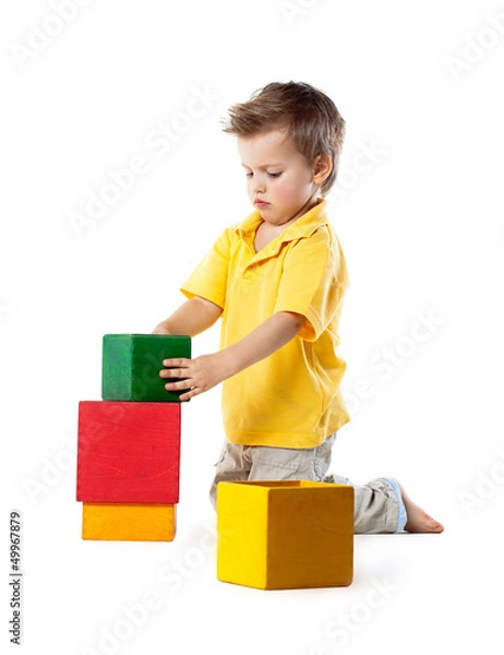 Fototapeta little boy plays with cubes, isolated on white