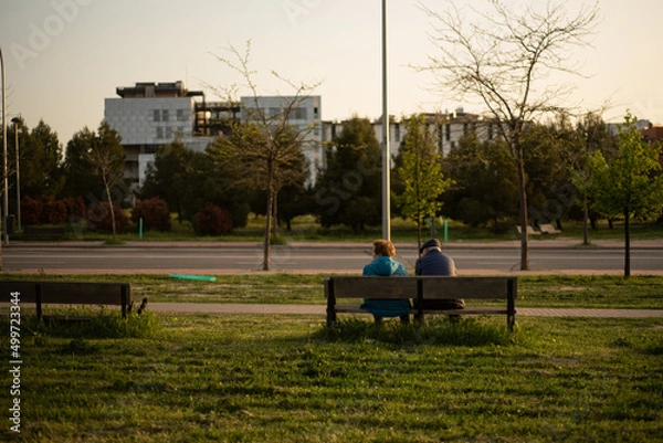 Fototapeta elderly couple sitting at sunset park 