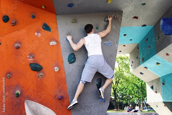 Obraz Bouldering - Man practicing rock climbing on artificial wall outdoors.