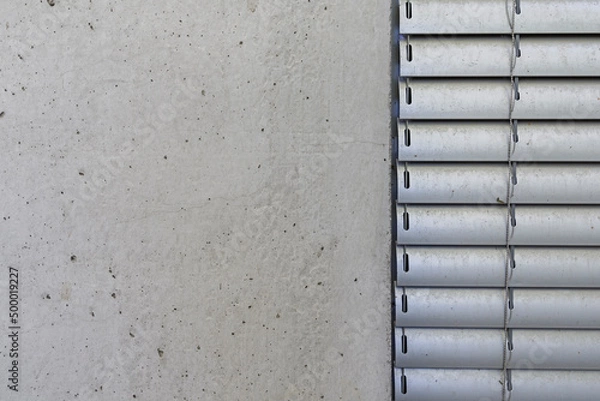 Fototapeta Detal architektoniczny na fragment elewacji domu jednorodzinnego wykonanego z betonu. Widoczny fragment żaluzji aluminiowych elewacyjnych.