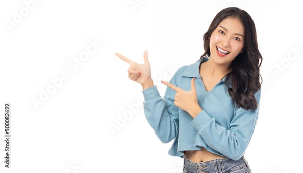 Fototapeta Beautiful young Asian woman pointing up to copy space and looking at camera with smile face and happy Pretty girl act like a satisfied product, use for advertising with isolated on white background