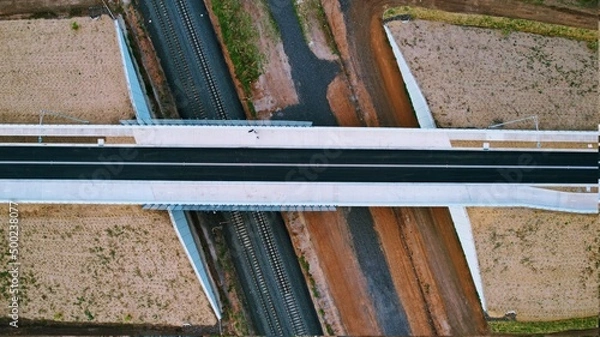 Obraz top down drone shot of a road bridge crossing over the train tracks