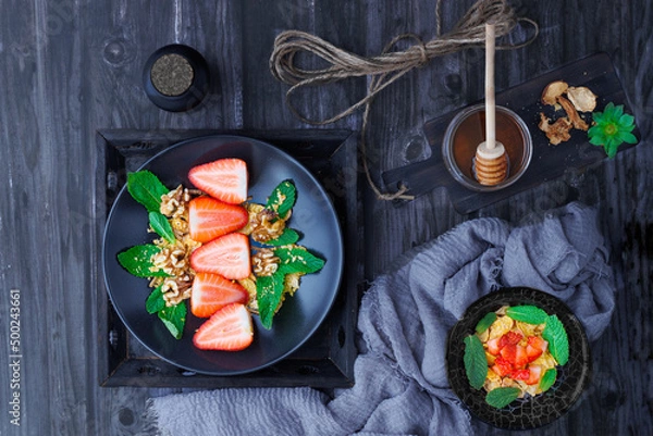 Obraz dark table with plates with strawberries, mint and nuts overhead view