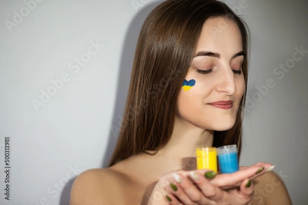 Obraz Ukrainian flag on the face of a young girl in support of Ukraine or the war