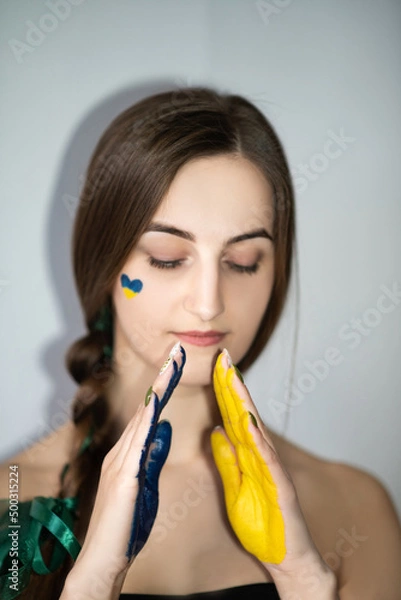 Obraz The girl prays with painted hands in the colors of the Ukrainian flag, no war