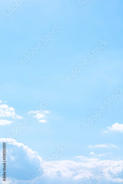 Fototapeta Soft fluffy cumulus clouds above the light blue sky in sunny day. Purity of natural white cloudscape scene with copy space. Vertical background. Freedom and calm of nature concept. Outdoor fresh air.