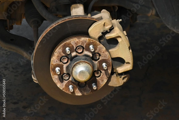 Fototapeta Closeup view of rusty truck front wheel hub at the garage, soft and selective focus.