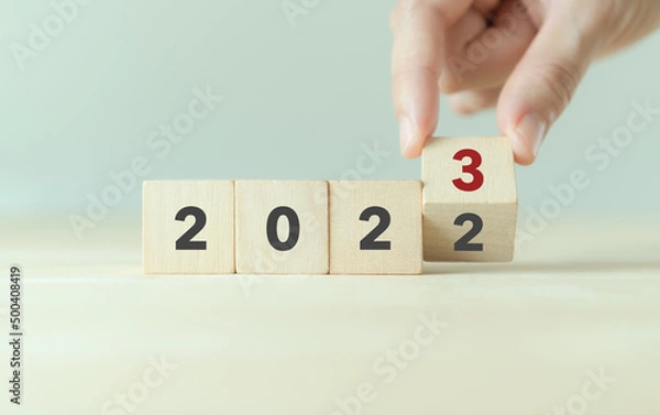 Fototapeta Beginning and start of the new year 2023. Preparation for happy new year ,new life, new business, plan, goals, strategy concept. Hand flips wooden cubes with  2022 to 2023 on smart background.