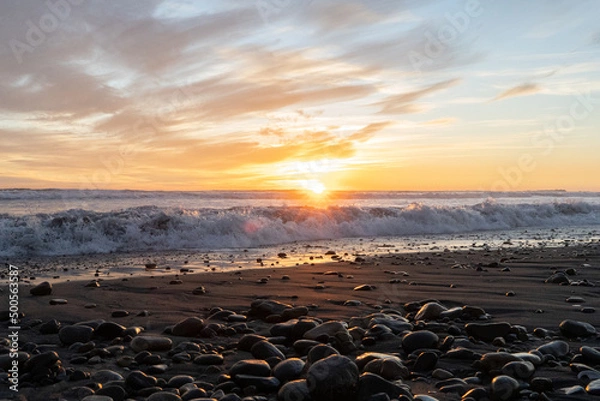 Fototapeta Lens flare horizontal shot of sunset with waves at Concón beach, Chile.