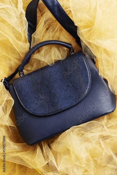 Fototapeta Women's handbag in blue on yellow textured background made of fabric.