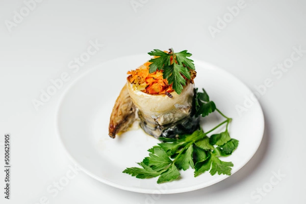 Fototapeta Baked fish on the fire with vegetables and decorated with carrots and greens on a plate