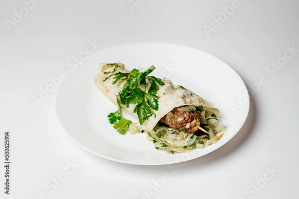Fototapeta Turkish kebab dish in pita bread with fresh salad on a wooden stick in a plate on a white background