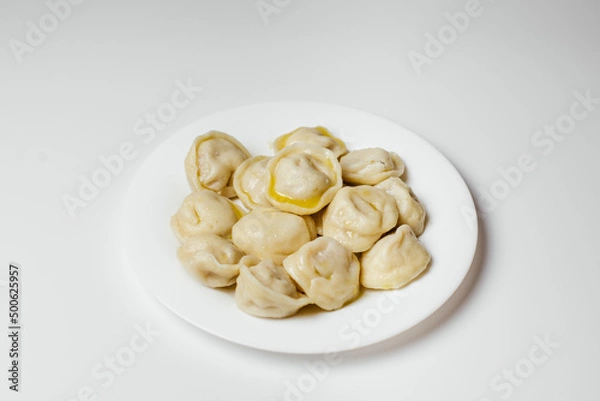 Fototapeta Hot delicious dumplings drizzled with butter in a plate on a white background