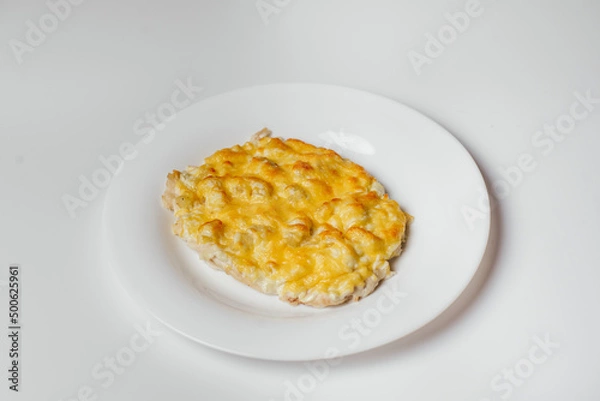 Fototapeta French meat baked in the oven with grated cheese on a white background in a plate