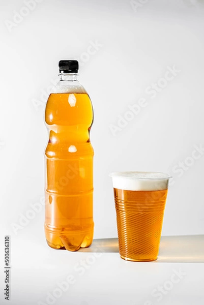 Fototapeta Fresh light draft beer in a plastic bottle. Beer with foam poured into a glass on a white background