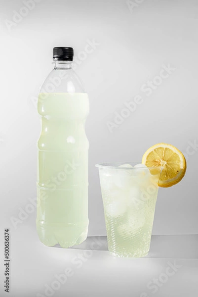Fototapeta Lemonade in a bottle. Lemonade in a glass with ice and decorated with a slice of lemon
