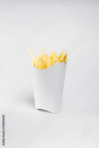 Fototapeta portion of french fries in a white box, fried potatoes in oil on a deep fryer