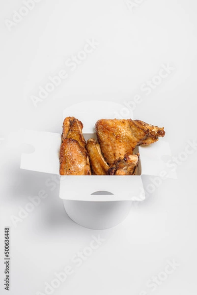 Fototapeta fried chicken wings in oil and breadcrumbs lie in a white box on a white background, top view