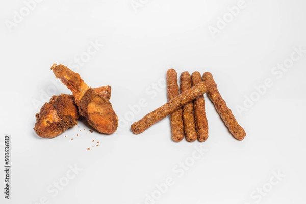 Fototapeta fried chicken drumsticks in oil and breadcrumbs lie on a white background in two pieces with chopsticks