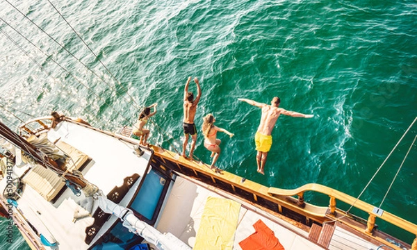 Fototapeta Top view of trendy adventurous friends jumping from sailboat on sea ocean trip - Millennial guys and girls having fun at exclusive boat party - Luxury vacation life style concept on bright filter