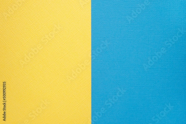 Fototapeta Two colored papers with a blue and yellow overlay on the floor. they divide half of the image. . High quality photo