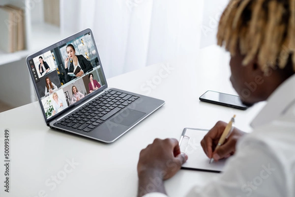 Fototapeta Business webinar. Video chat. Distance education. Guy watching online lesson with female coach speaking students taking notes on laptop screen in virtual class.
