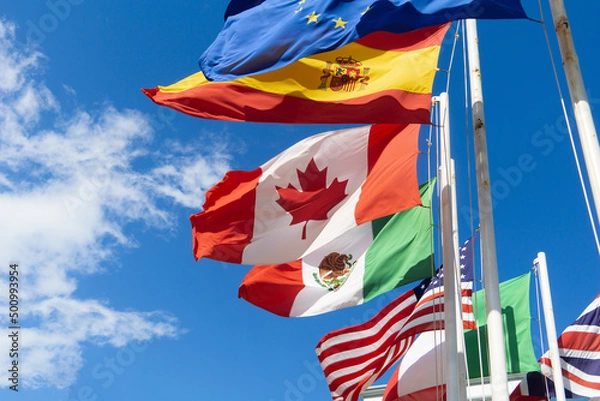 Fototapeta Flags of Canada, Spain, Mexico, the European Union, the USA are developing against the sky. Flags of different countries on flagpoles, the concept of negotiations and international relations.