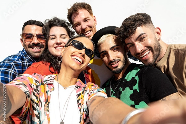 Obraz Group of happy young friends having fun and laughing while taking a selfie with mobile phone. Diverse millennial people spending time together.