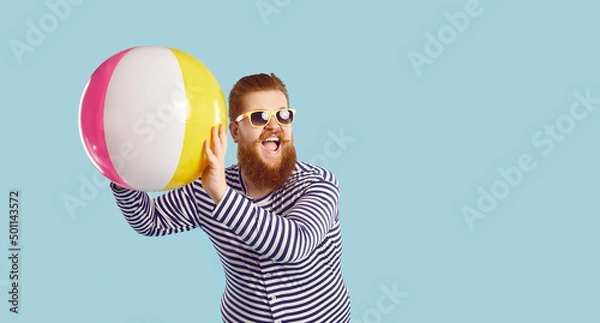 Fototapeta People, summer vacation, vacation and lifestyle. Banner.Cheerful funny guy in sunglasses playing with beach inflatable ball on pastel blue background. Bearded chubby man having fun near copy space.