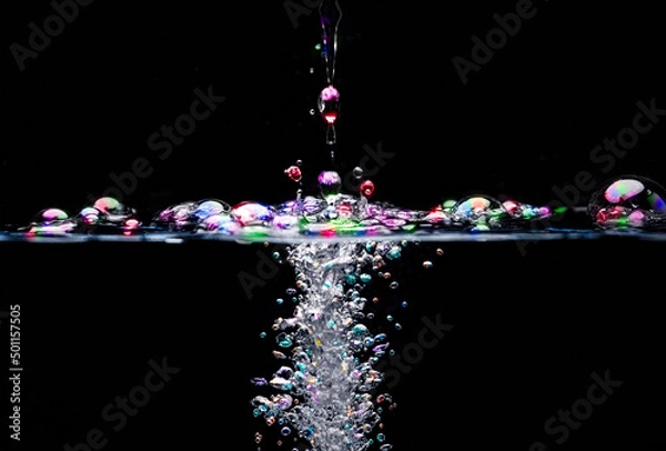 Obraz A heavy object dropped into clear water, creating many bubbles above and below the surface.  The bubbles have been coloured, for extra impact.