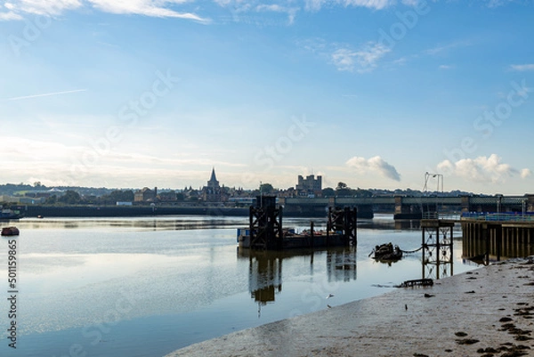 Obraz Rochester Castle and Cathedral, from East of the Rochester Bridge, across the Medway River.  A clear autumn day in October 2021. A derelict jetty and dockside equipment are in the river. 